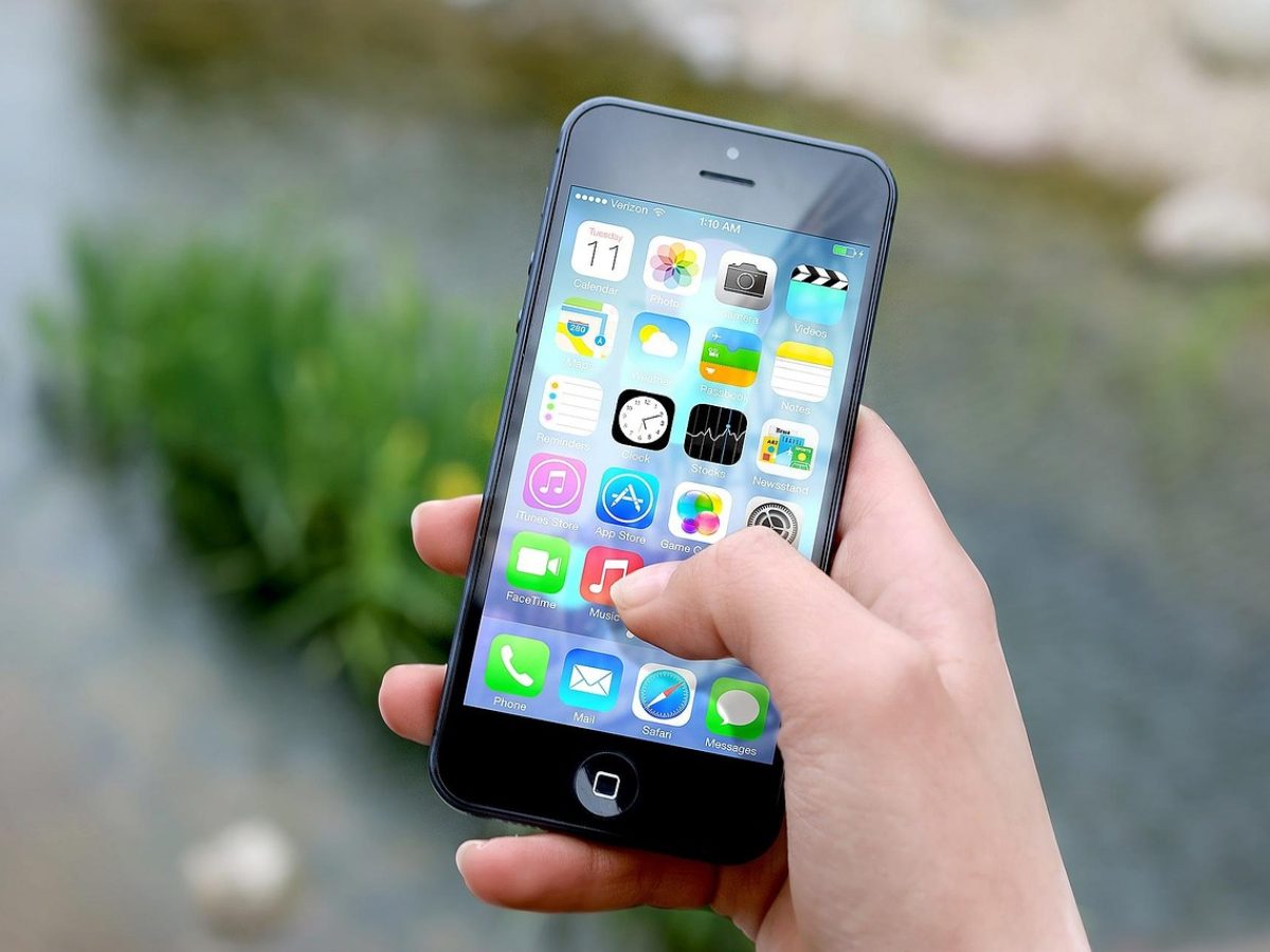 导航在线观看 App 首页界面在手机屏幕上的展示，深玫红玻璃质感背景中排列着分类索引卡片，暖色灯光映在桌面上